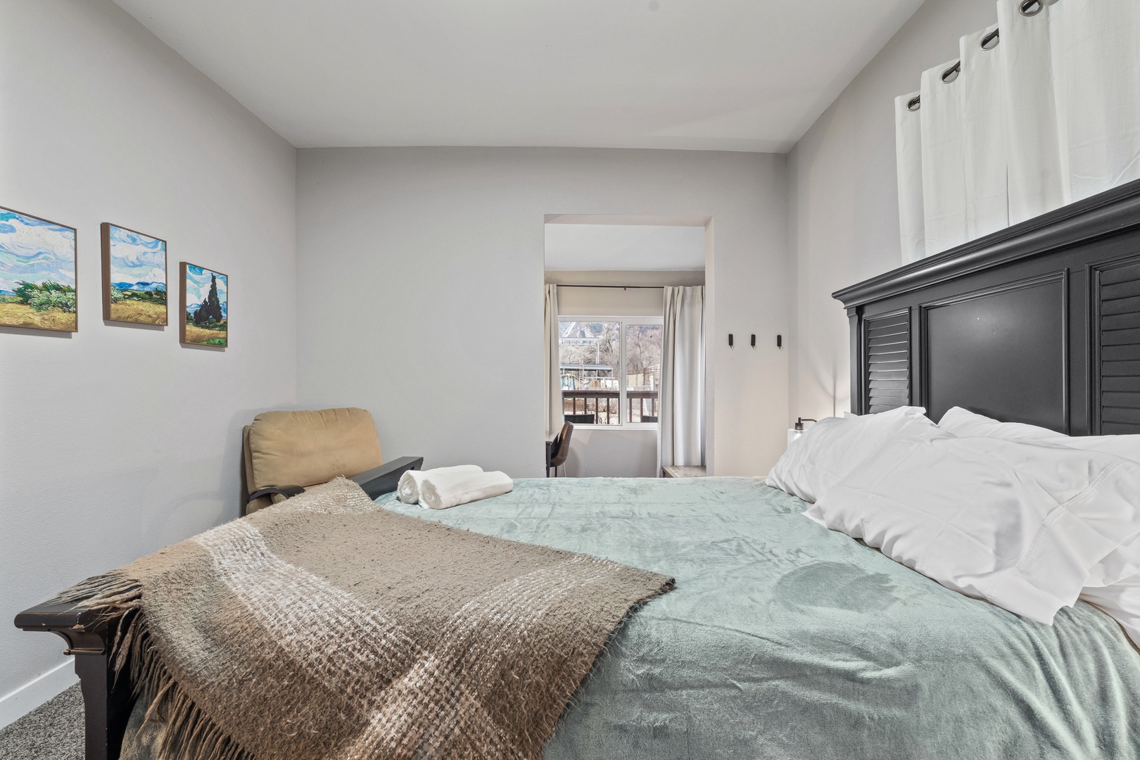 Relax in your comfortable bedroom featuring a stylish dark wood headboard, cozy textured bedding, and charming artwork that creates a peaceful retreat for your stay.