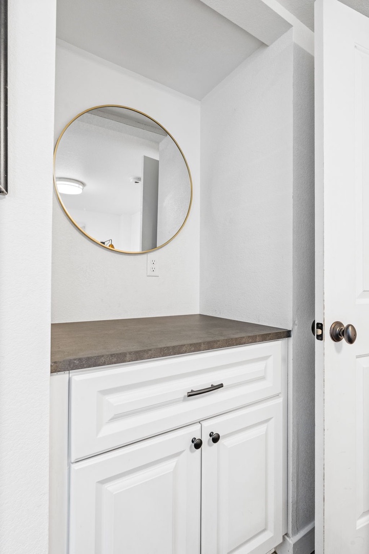 Refresh in your stylish bathroom featuring crisp white cabinetry, sleek concrete countertops, and a chic gold-rimmed mirror.