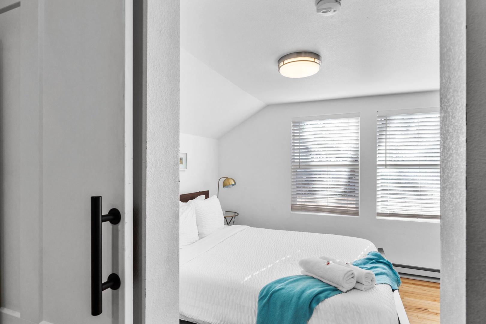 Step into your cozy bedroom retreat with crisp white linens and soft natural light filtering through the blinds.