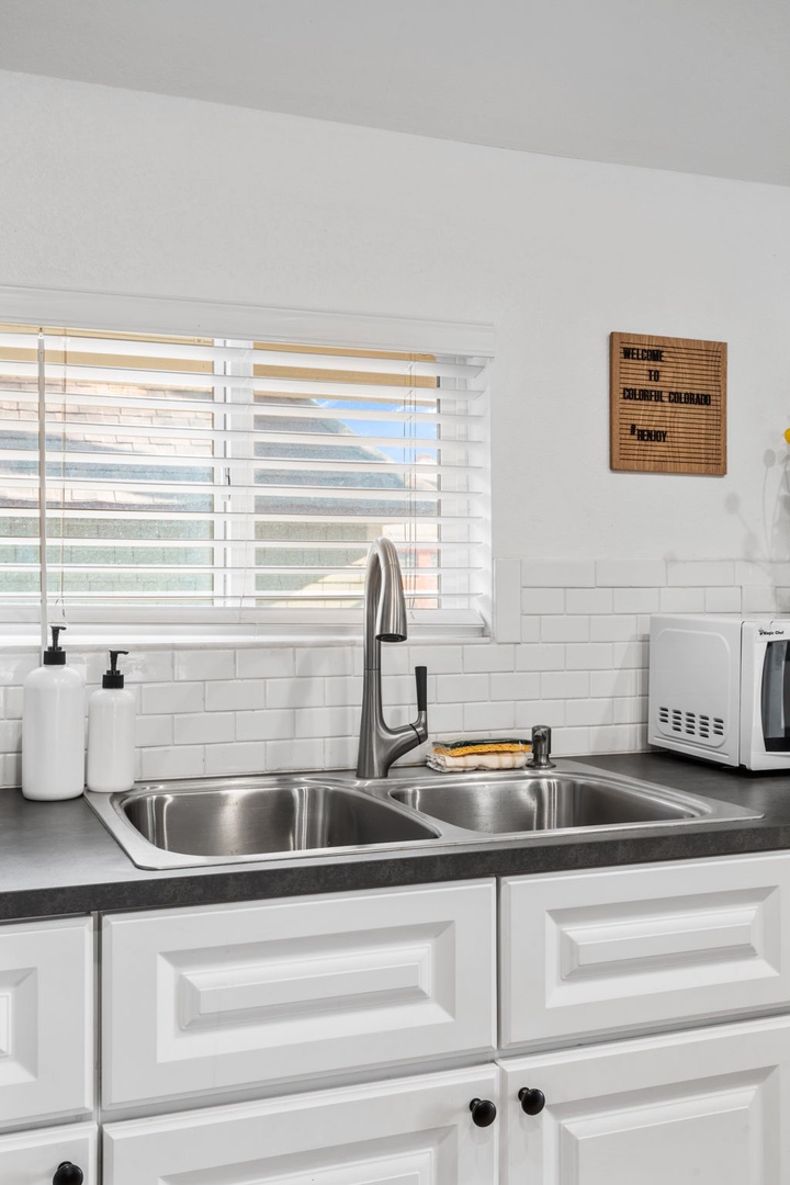 Your bright kitchen features a sleek double sink, modern faucet, and microwave - perfect for preparing meals during your stay.
