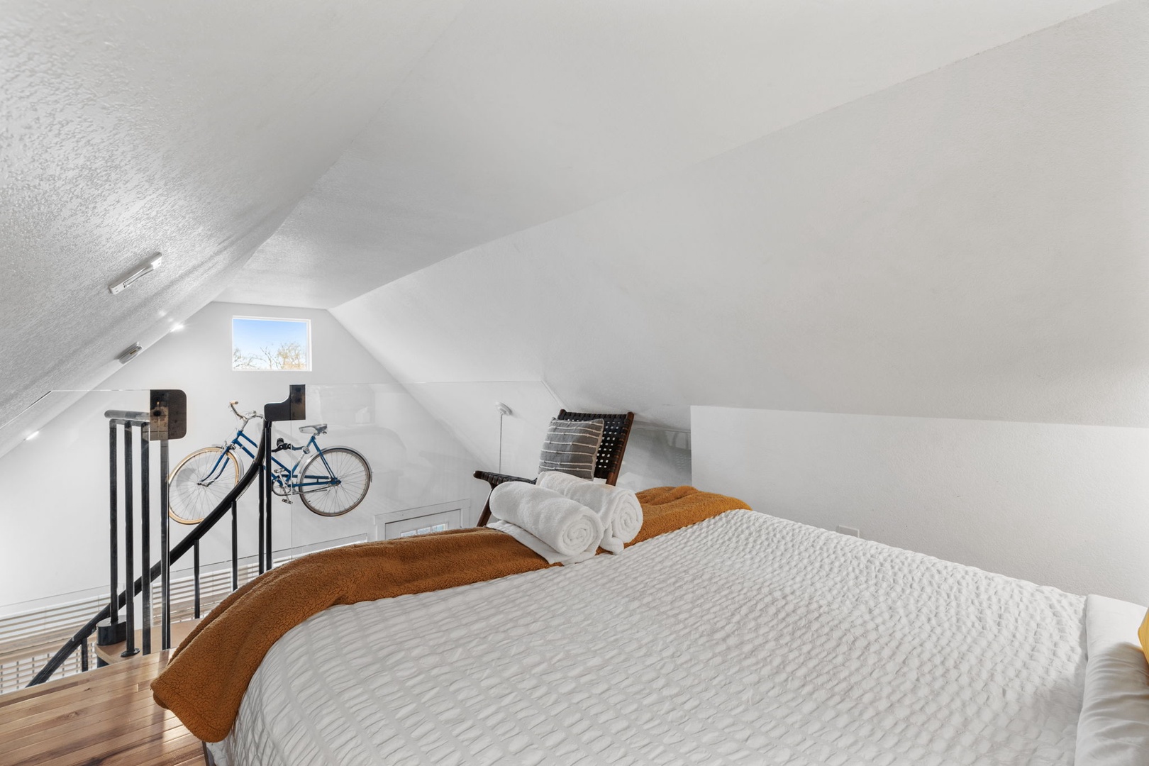 Your cozy loft bedroom awaits with crisp linens and warm accents under slanted ceilings.