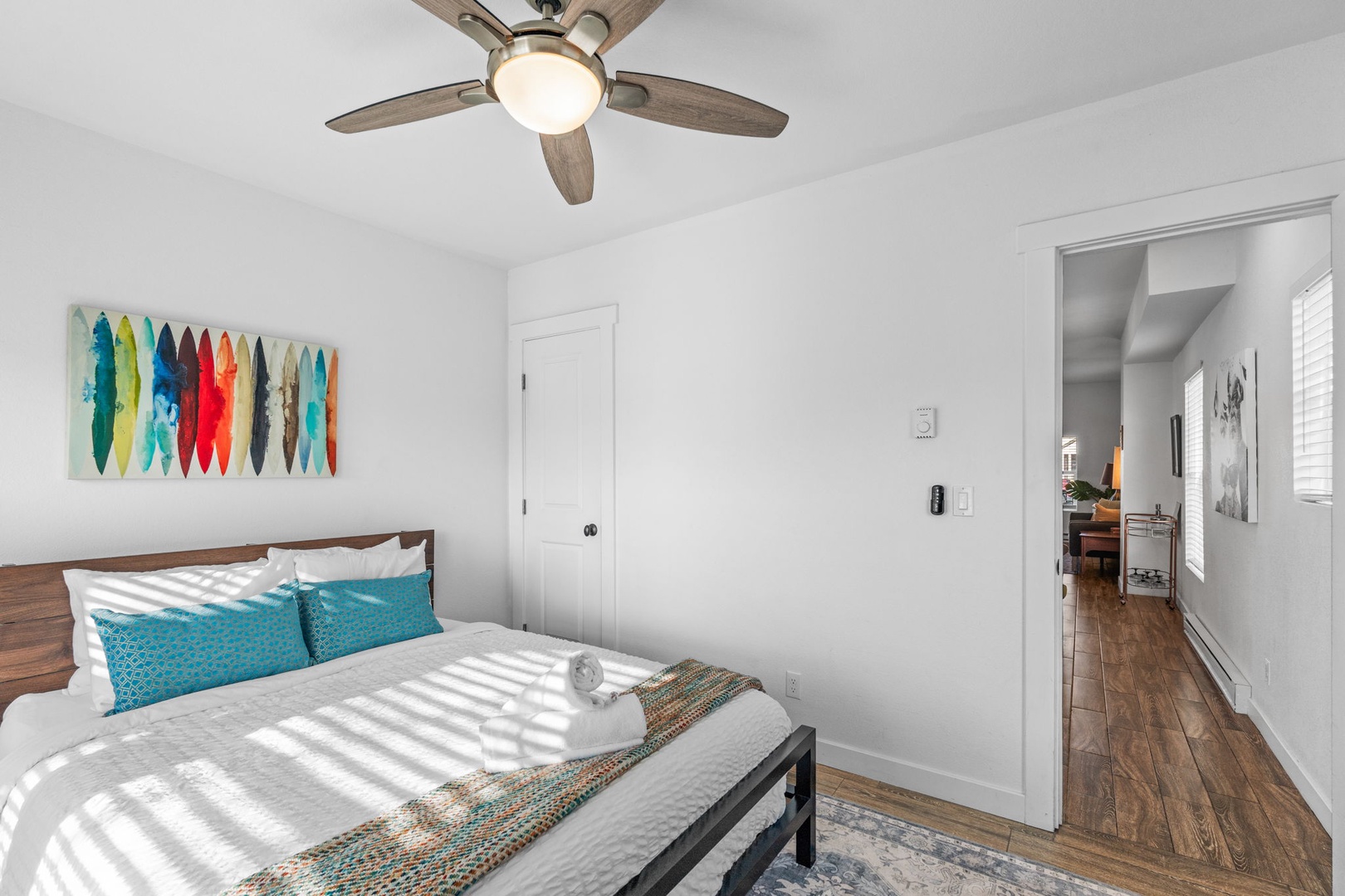 Drift off in your coastal-themed bedroom where vibrant surfboard art and gentle ceiling fan create your perfect sleep sanctuary.
