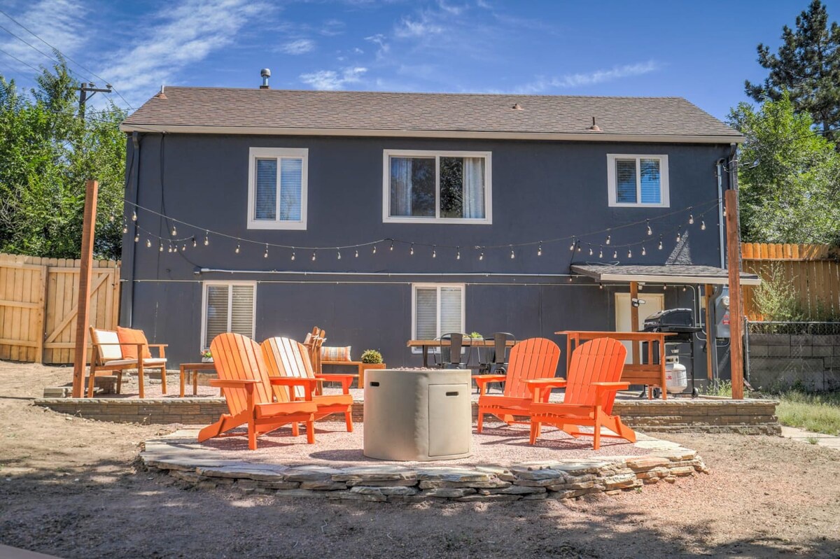 Contemporary two-story rental with bright orange Adirondack chairs surrounding a fire pit, creating the perfect gathering spot for evening conversations.