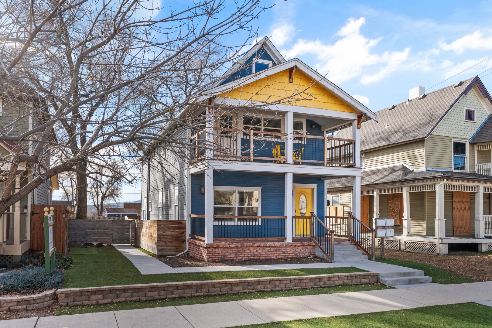 Charming blue and yellow craftsman home featuring a welcoming front porch and well-maintained landscaping in a quiet residential neighborhood.