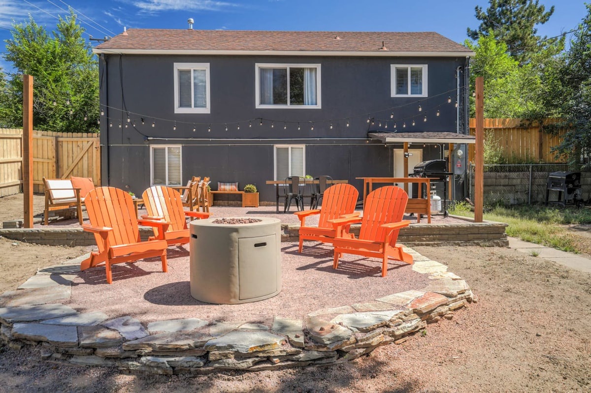 Gather around your private fire pit on cozy orange Adirondack chairs, sharing stories under twinkling string lights in this peaceful backyard retreat.