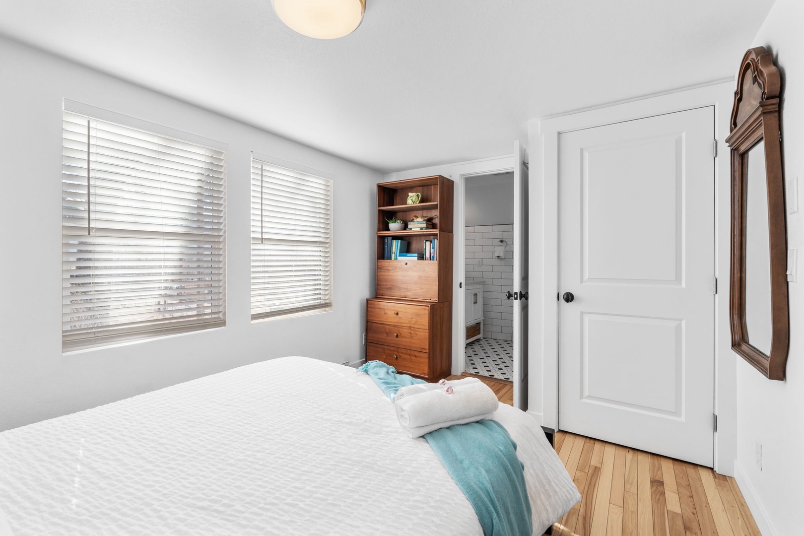 Drift off in this peaceful bedroom with soft linens, warm wood floors, and your own ensuite bathroom steps away.