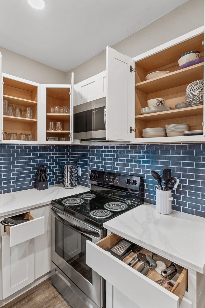 Your fully equipped kitchen features white cabinetry, stainless steel appliances, and a striking blue subway tile backsplash - everything you need to prepare your favorite meals.