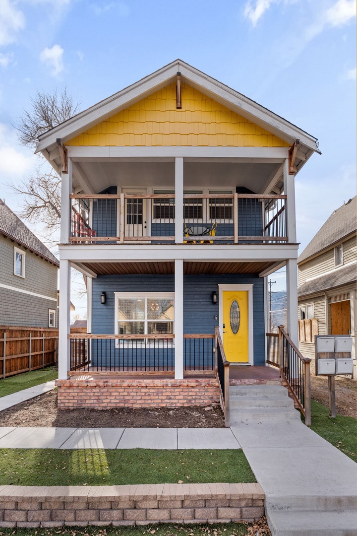Charming two-story home with bright yellow accents and welcoming front porch in a peaceful neighborhood setting.