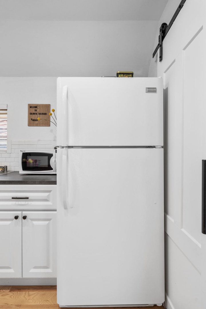 Your fully-equipped kitchen includes a spacious refrigerator and microwave, perfect for storing fresh groceries and preparing quick meals.