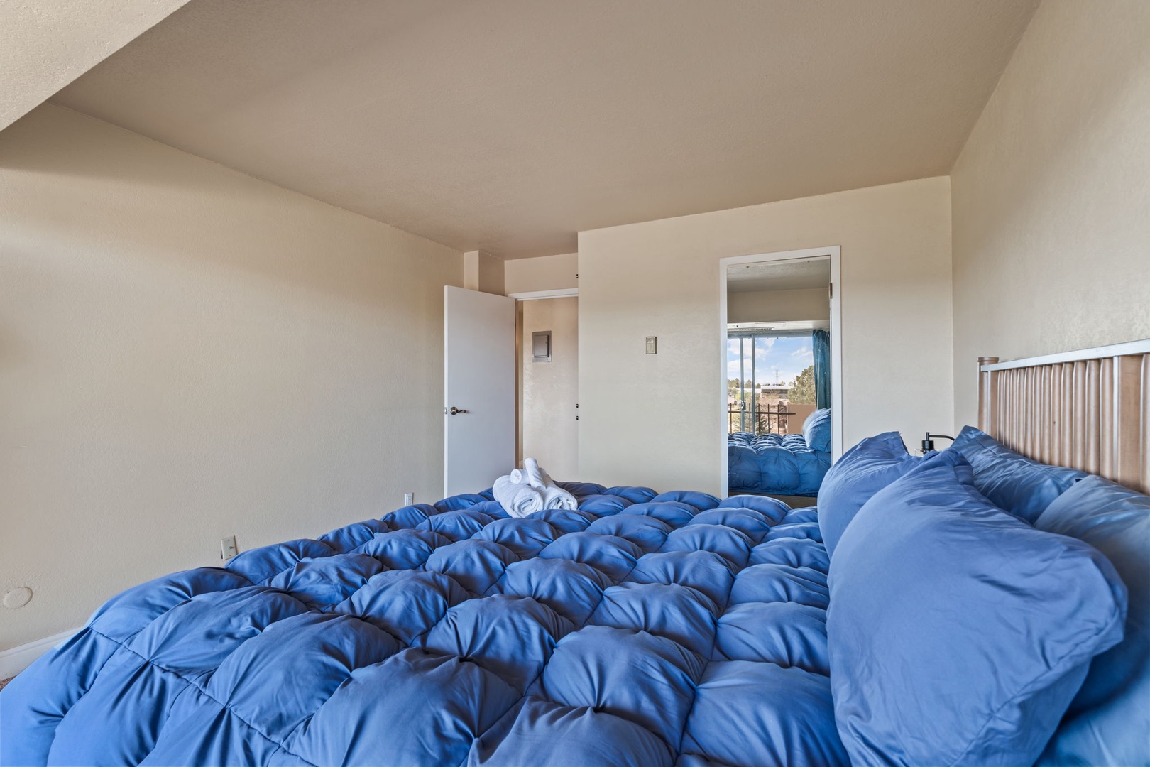 Your cozy bedroom awaits with a plush blue comforter and fresh towels, promising restful nights. The bright, connected layout invites you to unwind in comfort.