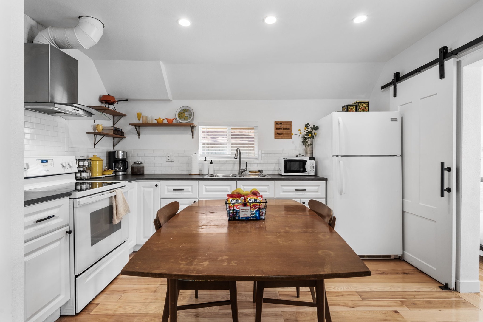 Your fully equipped kitchen invites culinary adventures with modern appliances, rustic wood table for family meals, and charming sliding barn door adding farmhouse flair.