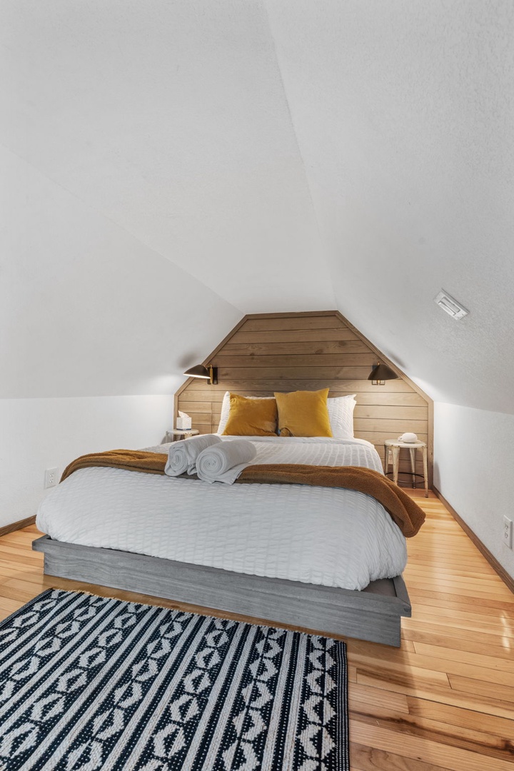 Your cozy attic retreat features warm wood accents and golden pillows, creating the perfect hideaway for restful nights.