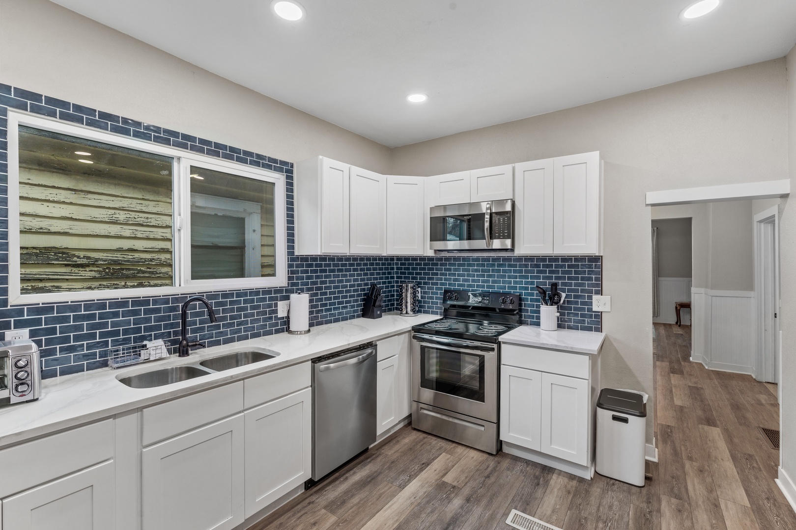 Your fully equipped kitchen features modern stainless steel appliances, elegant white cabinetry, and a striking blue subway tile backsplash for all your culinary needs.