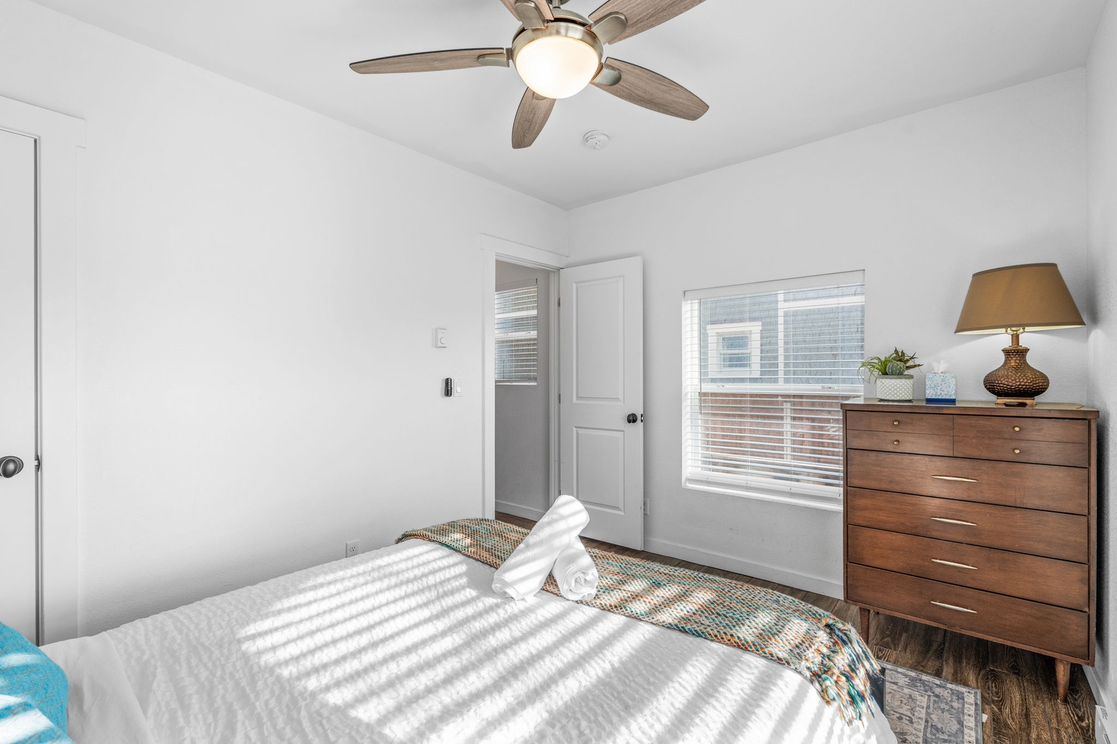 Rest peacefully in this bright bedroom with comfortable furnishings, ceiling fan, and natural light streaming through your window.