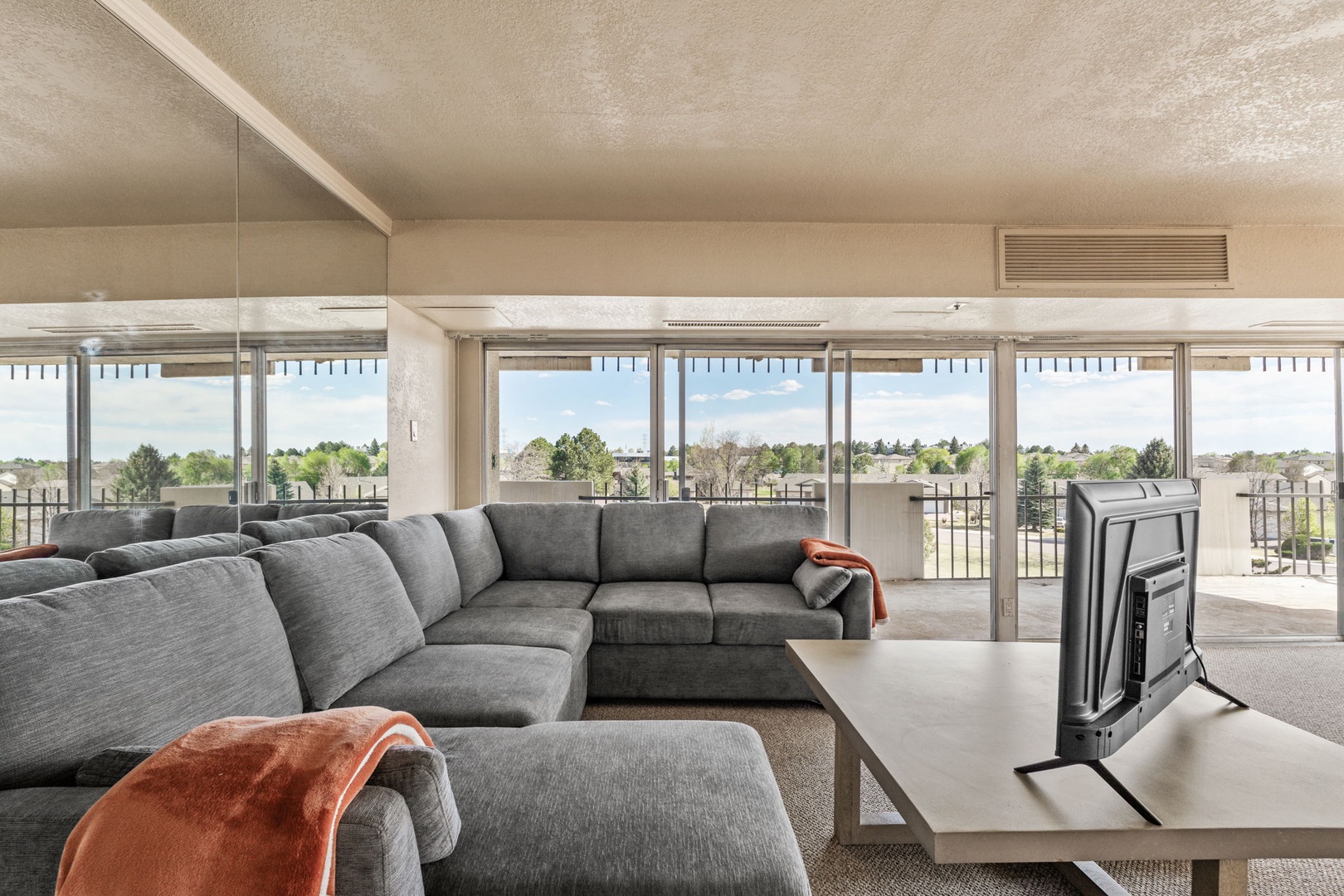 Sink into plush seating while taking in sweeping views through floor-to-ceiling windows that frame the lush landscape beyond. Your retreat awaits in this bright, open-concept living space.