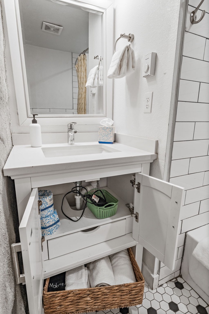 You'll love this thoughtfully organized bathroom vanity with fresh towels, convenient storage, and charming details.