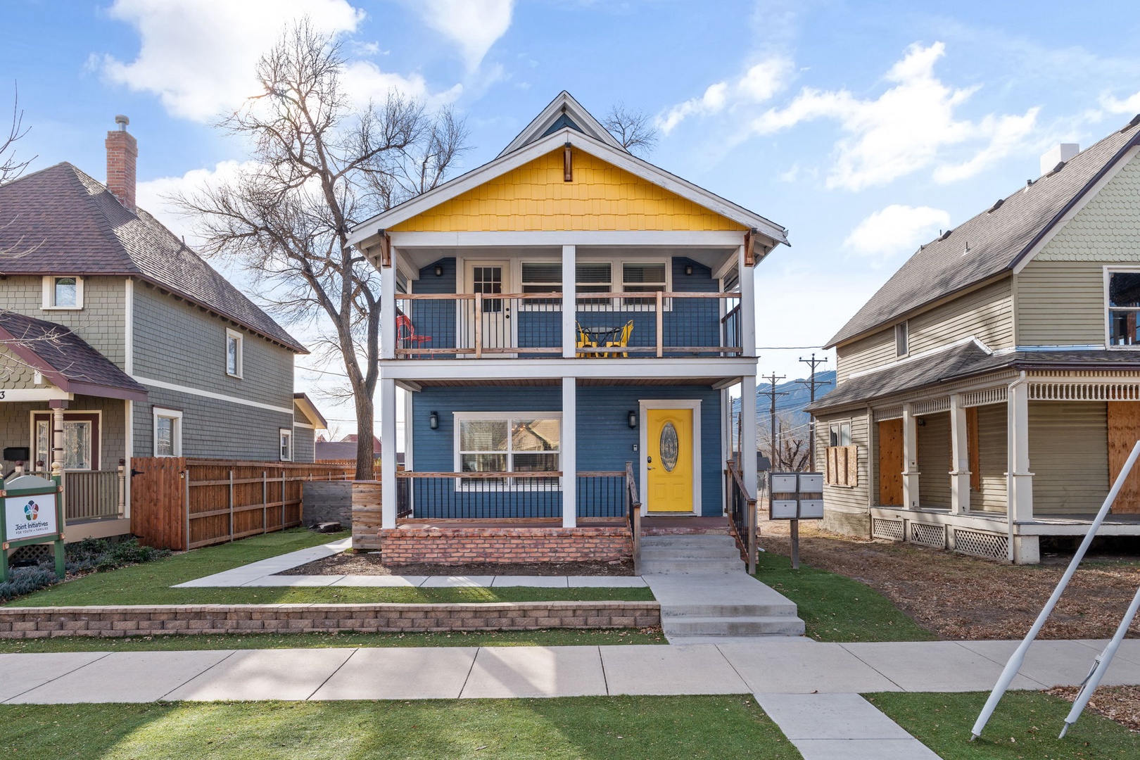 This charming two-story home with bright yellow accents and inviting front balcony sits perfectly in a friendly neighborhood setting.