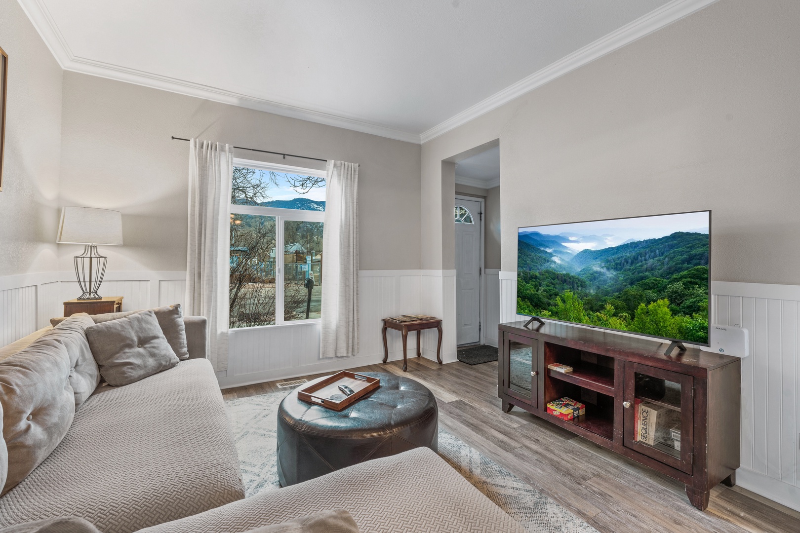 Relax in your comfortable living area with plush seating, entertainment center, and peaceful mountain views through the large window.