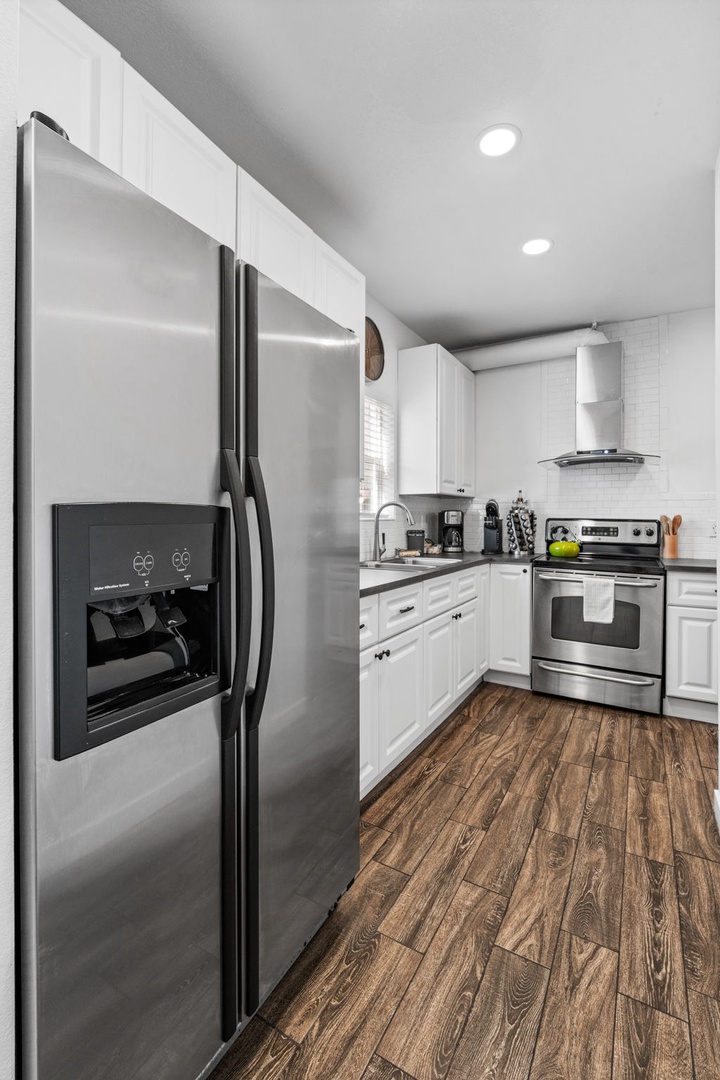Prepare your favorite meals in this fully equipped kitchen featuring stainless steel appliances, ample counter space, and modern white cabinetry.