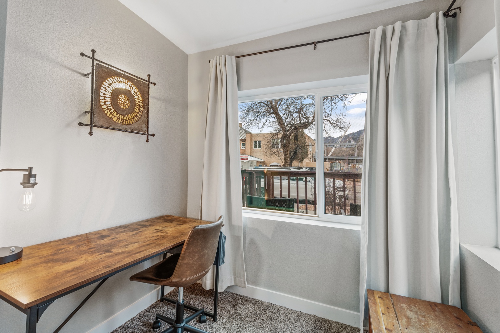 Stay productive in your dedicated workspace with a stylish wood desk and comfortable seating, featuring natural light from the neighborhood view.