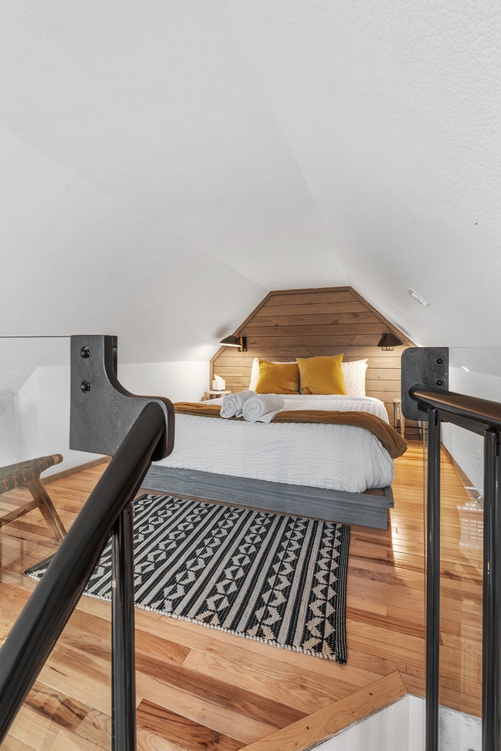 Climb into your cozy loft retreat where warm wood tones and soft lighting create the perfect sanctuary for rest.