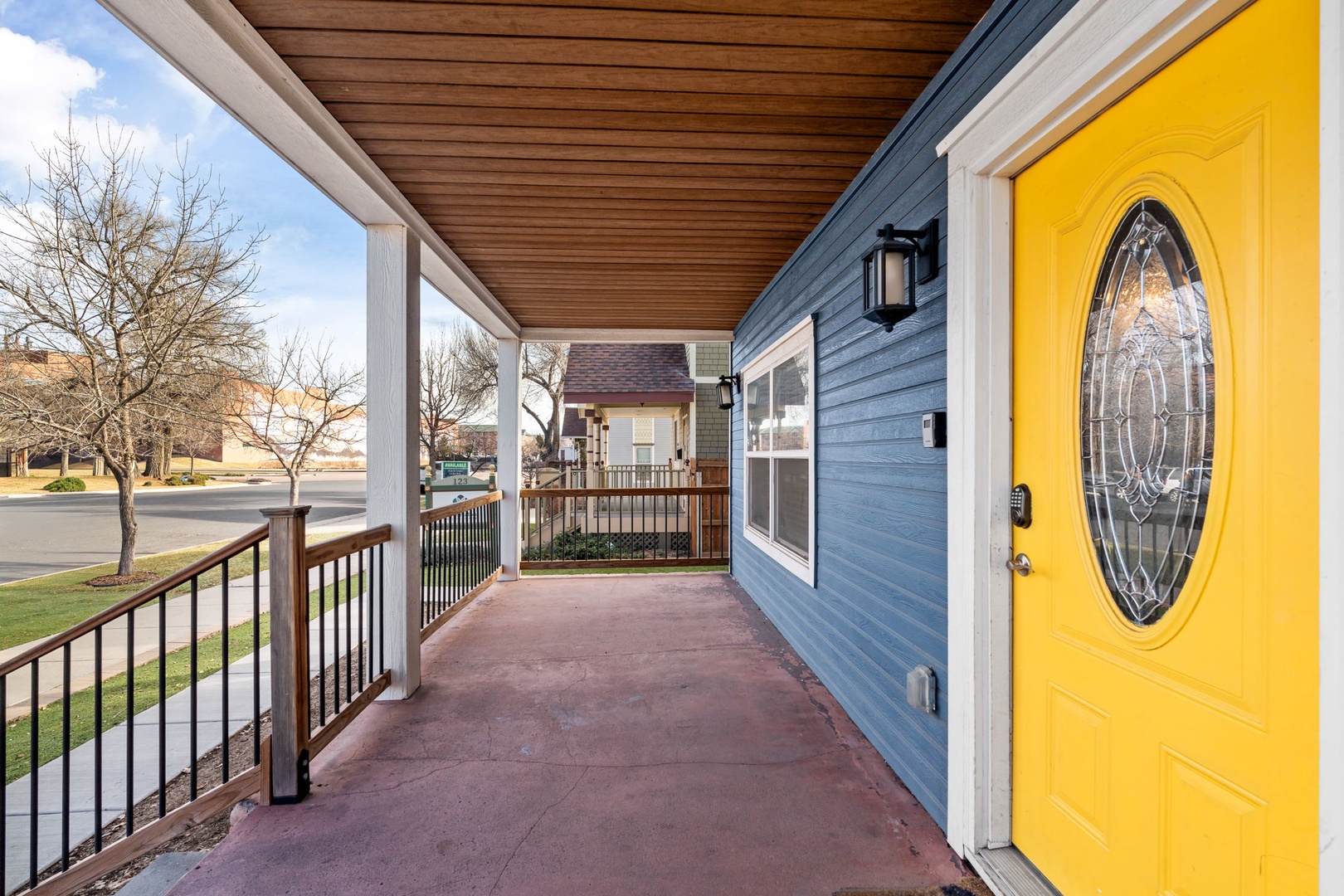 Charming blue home with welcoming bright yellow front door and covered porch in peaceful residential neighborhood.