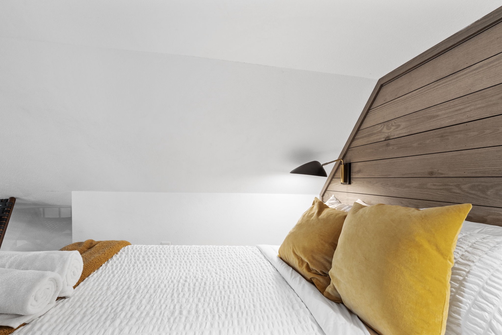 Sink into crisp white linens and plush golden pillows beneath your cozy wood headboard, where reading lights create perfect bedtime ambiance.