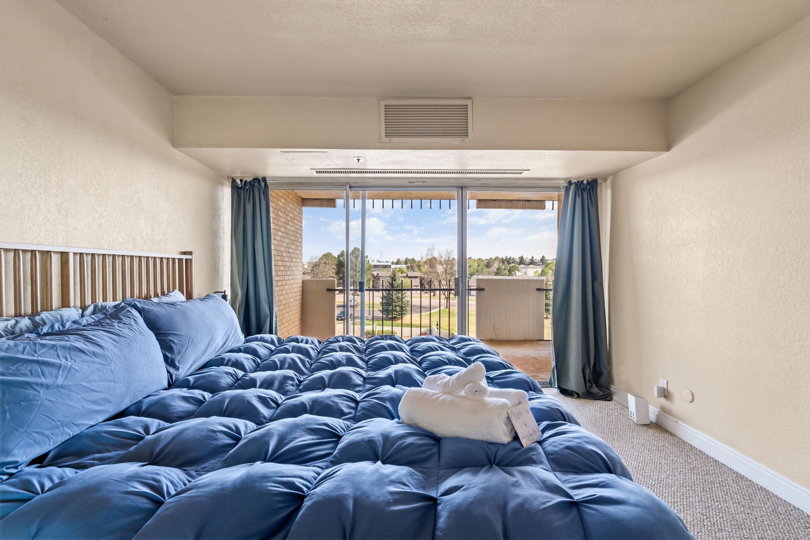 Wake up to bright morning light streaming through your private balcony doors. Cozy blue linens invite you to relax while the neighborhood view reminds you there's a whole world waiting to explore.