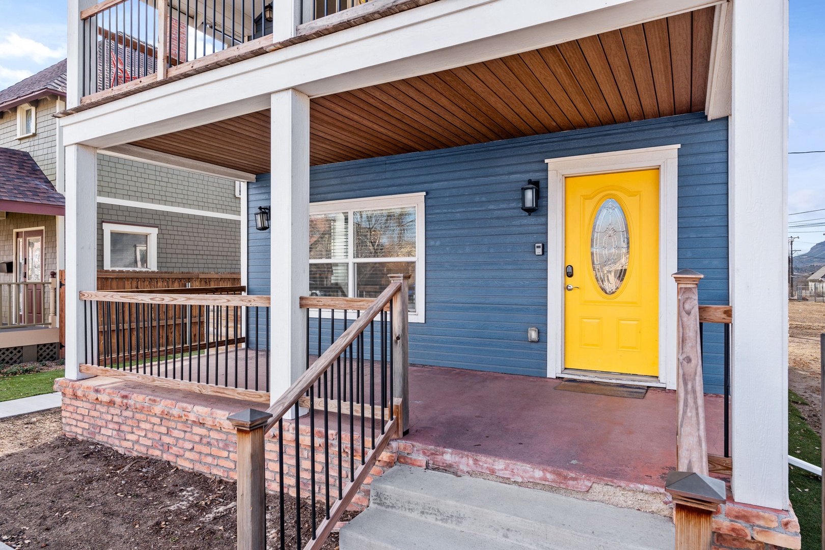A welcoming entrance with blue siding and bright yellow door creates a cheerful first impression for your arrival.