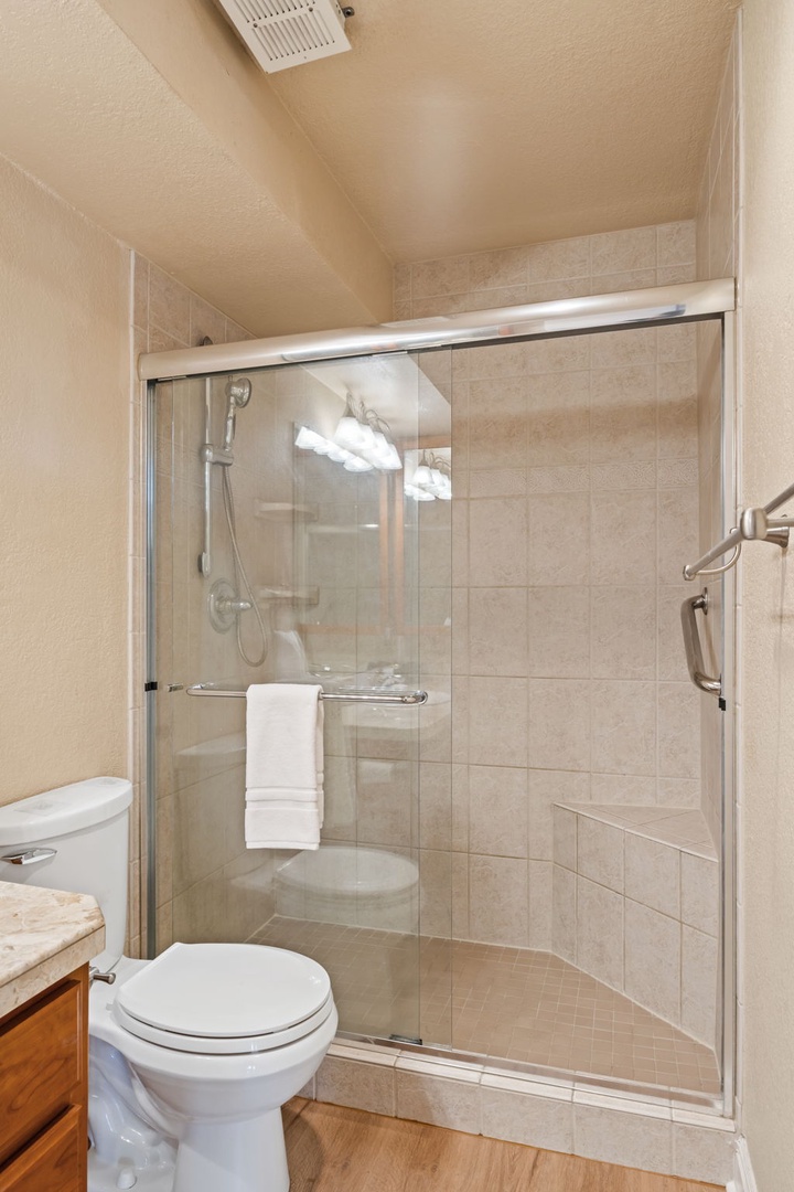 A bright, accessible bathroom with a spacious walk-in shower featuring grab bars and a handheld showerhead for your comfort and safety.