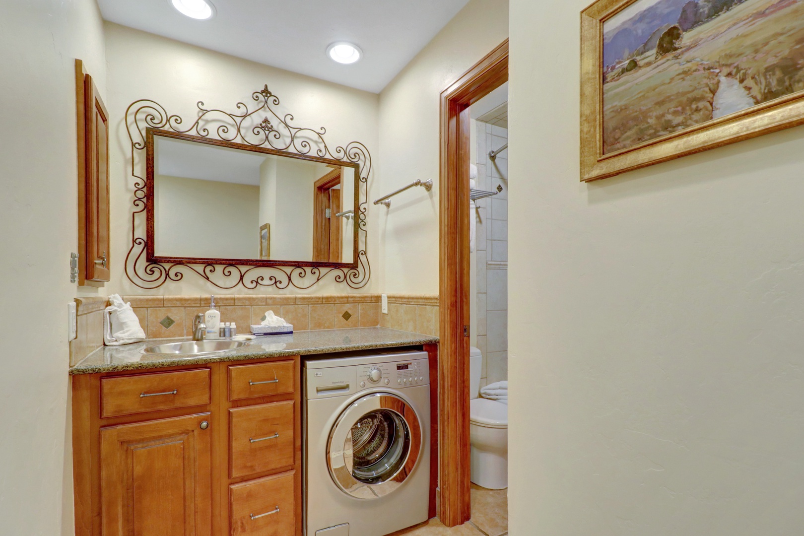 Convenient bathroom featuring a tiled tub/shower combination and an in-unit washer/dryer with granite countertop. Perfect for extended stays and family convenience.
