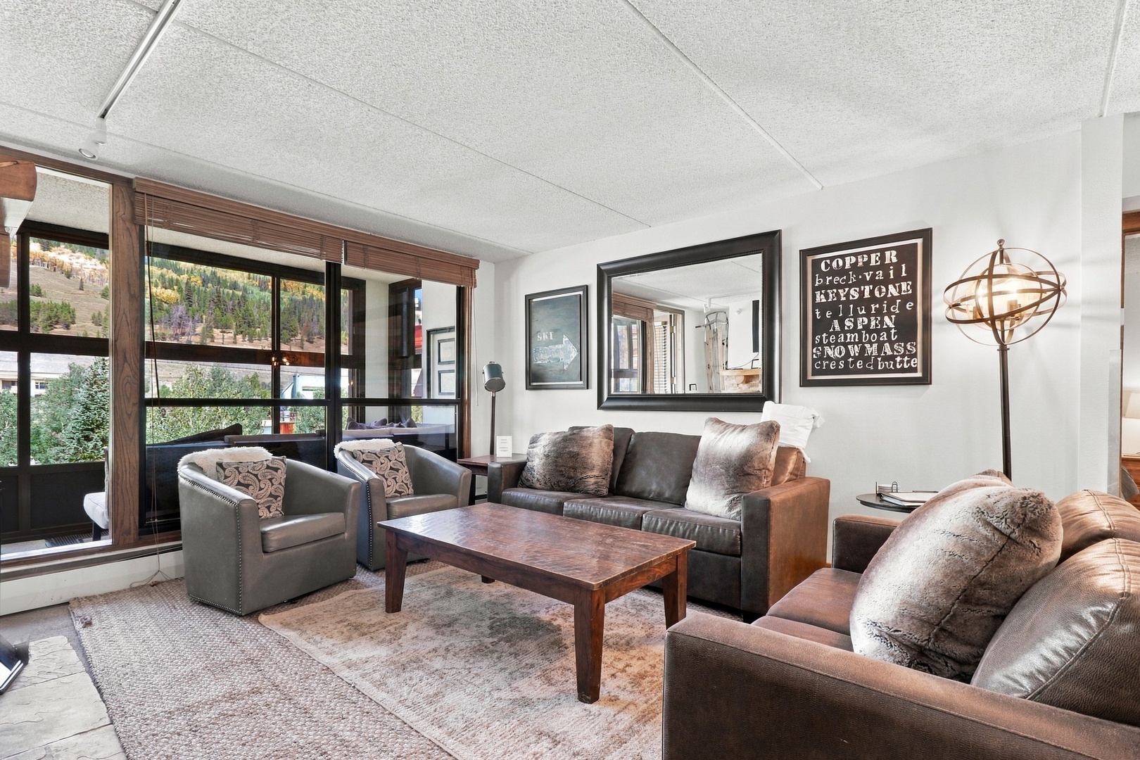 Your cozy mountain living room awaits with plush leather seating, rustic wood accents, and windows framing scenic views—perfect for unwinding after your day exploring nearby slopes and trails.