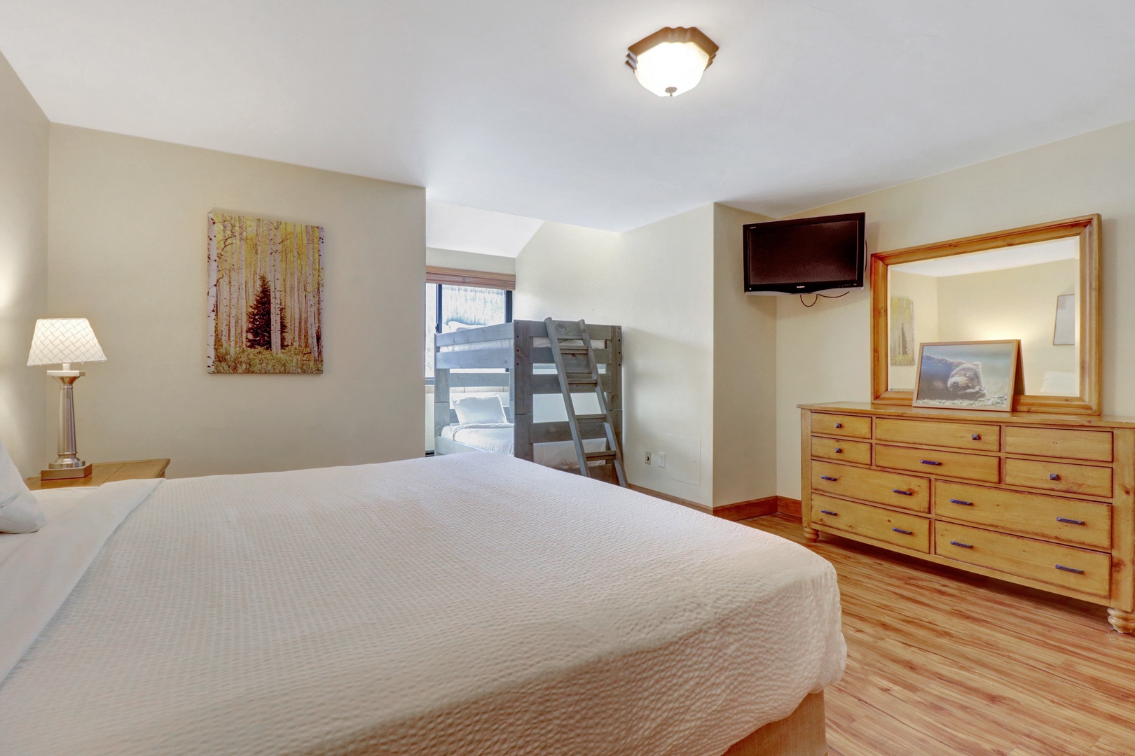 Spacious bedroom featuring a comfortable king bed, additional bunk beds for extra guests, and a wall-mounted TV. Ideal for families or groups enjoying the mountain.