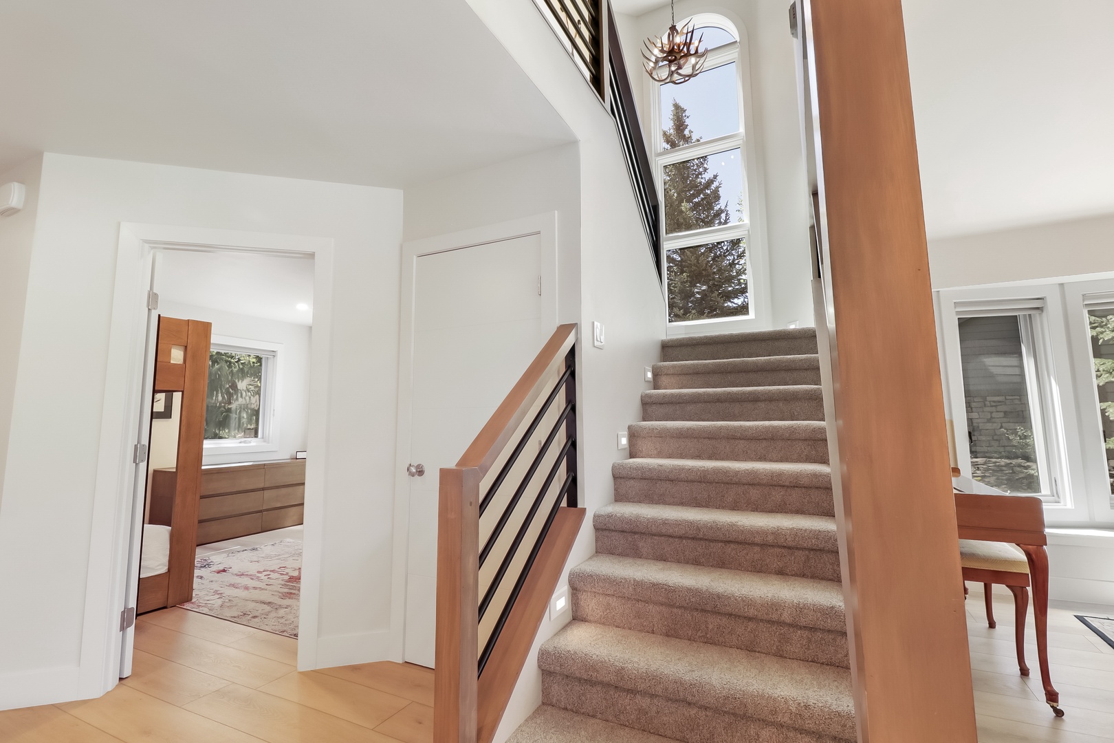 Sunlight pours through tall windows onto this inviting staircase, where rustic touches and thoughtful design welcome you to explore your multi-level mountain retreat.