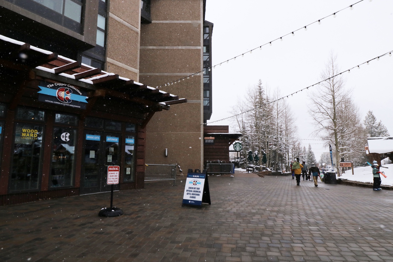 The property sits in a lively ski village area with mountain resort shops and cafes just steps away. Falling snow and string lights add charm to this winter setting.