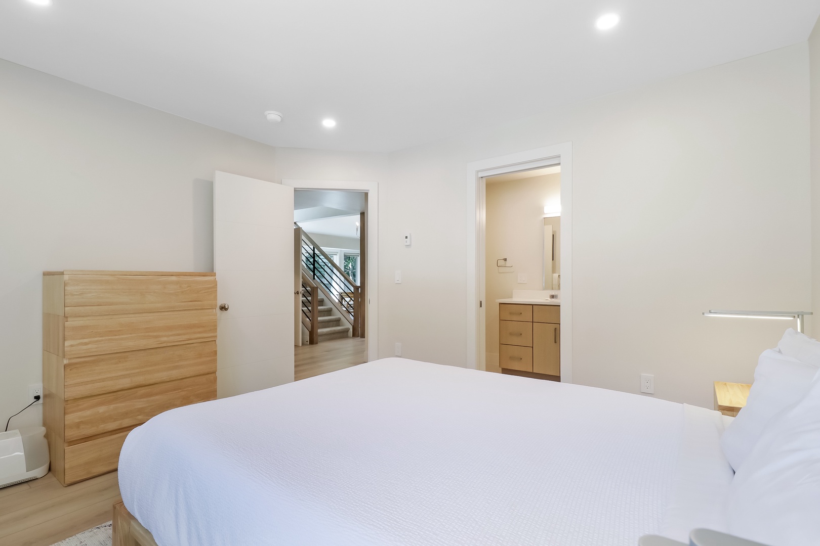 Drift off in this serene bedroom, where crisp linens and warm wood tones create your personal retreat. The en-suite and natural light promise restful mornings.