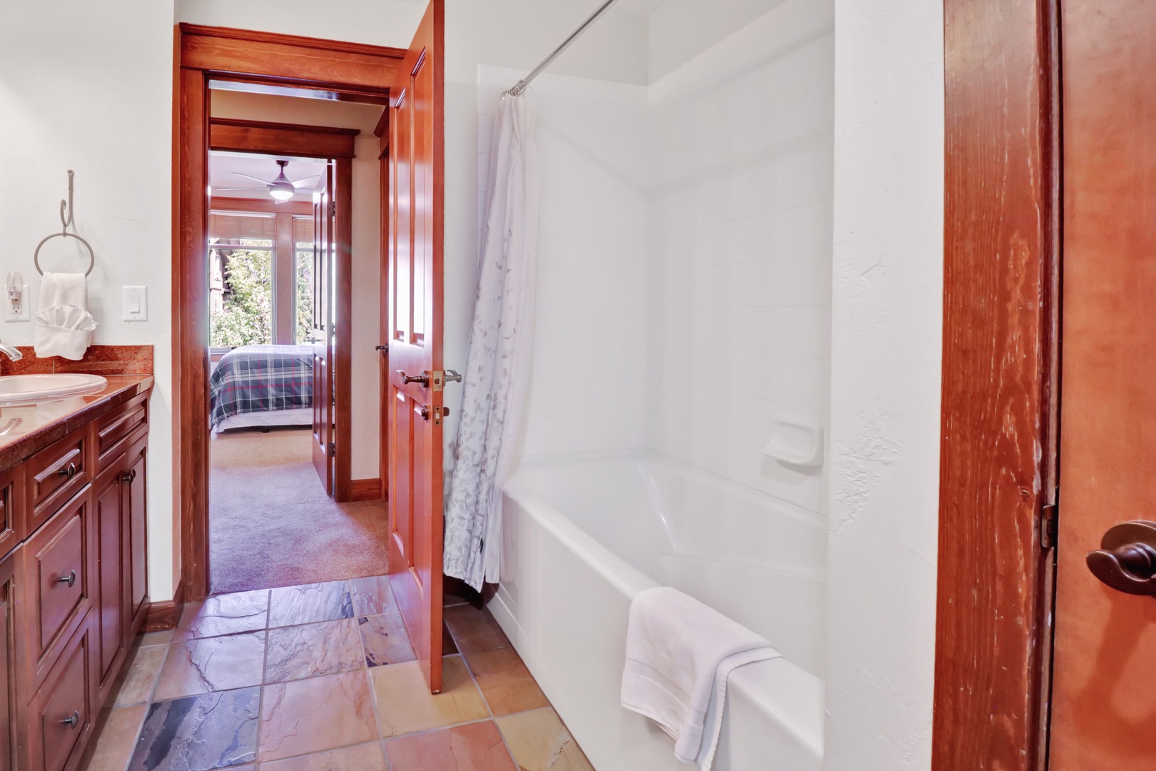 Step into your private en-suite, where warm wood tones and fresh towels await, with your cozy bedroom just beyond the door.