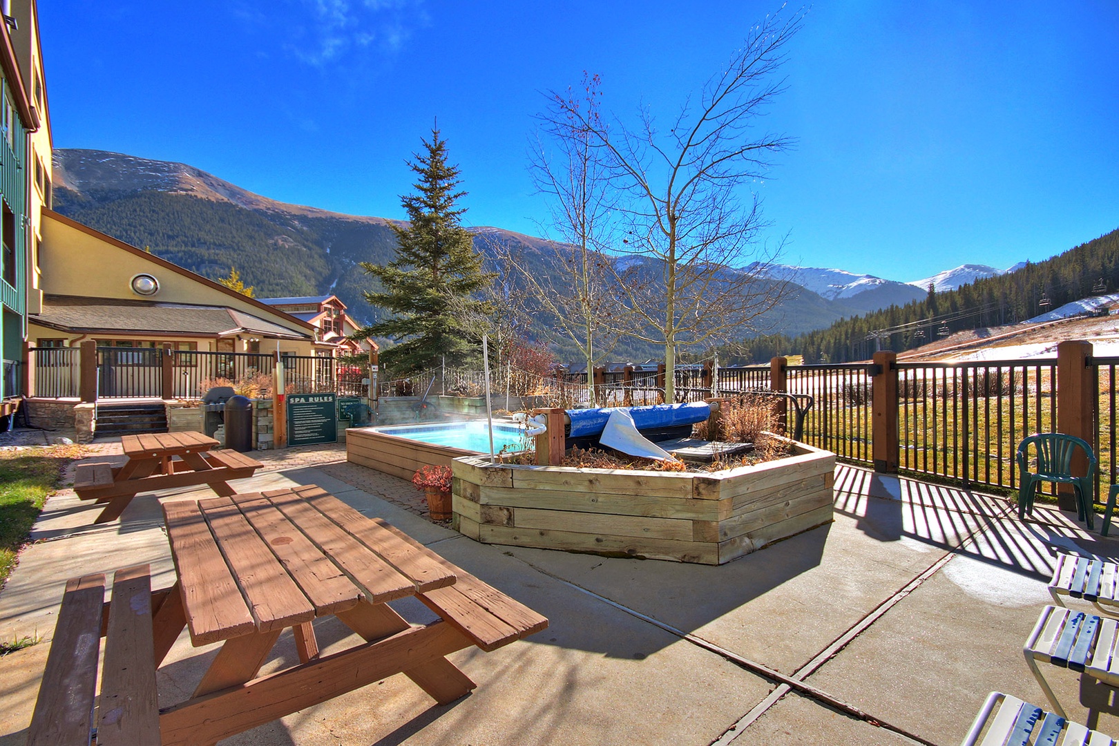 Soak in the hot tub while mountain peaks frame your perfect alpine retreat, where outdoor dining awaits under endless blue skies.