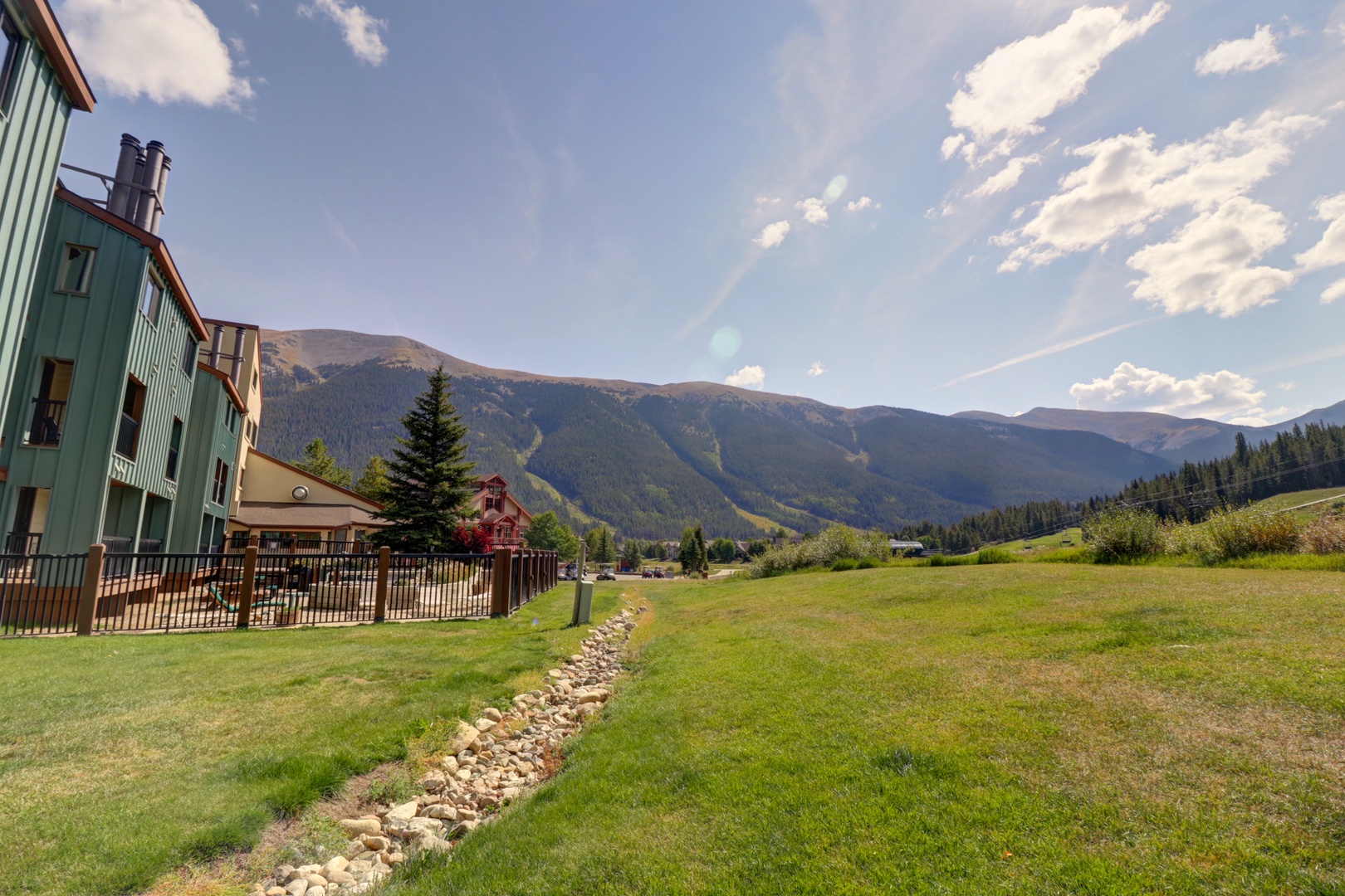 Mountain resort buildings nestled in a scenic alpine valley with expansive meadows and forested peaks creating a peaceful Colorado landscape.