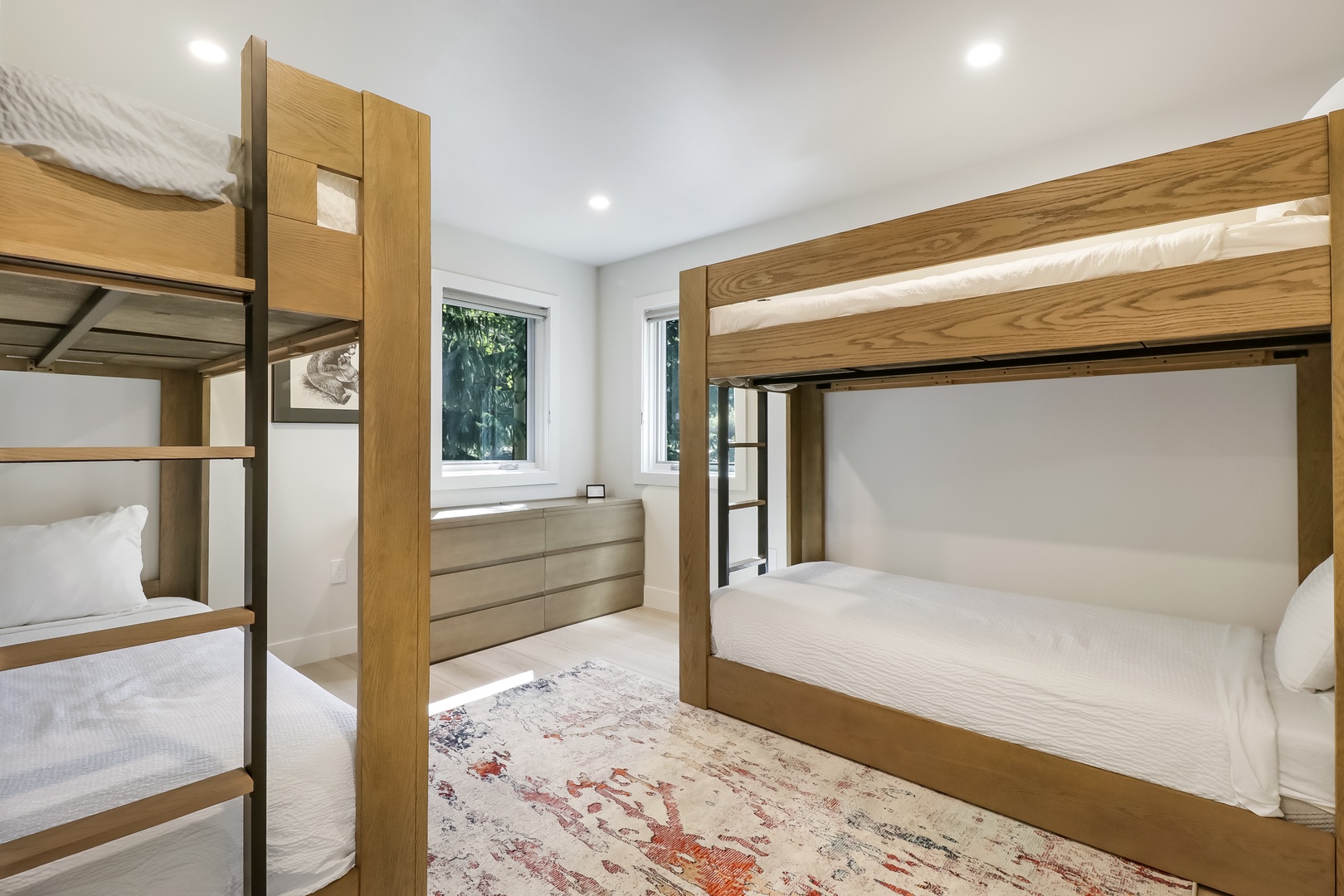 Unwind in this thoughtfully designed bunk room where everyone has their own cozy spot. Natural light streams through double windows, illuminating the warm wood tones and pristine linens that promise restful nights.