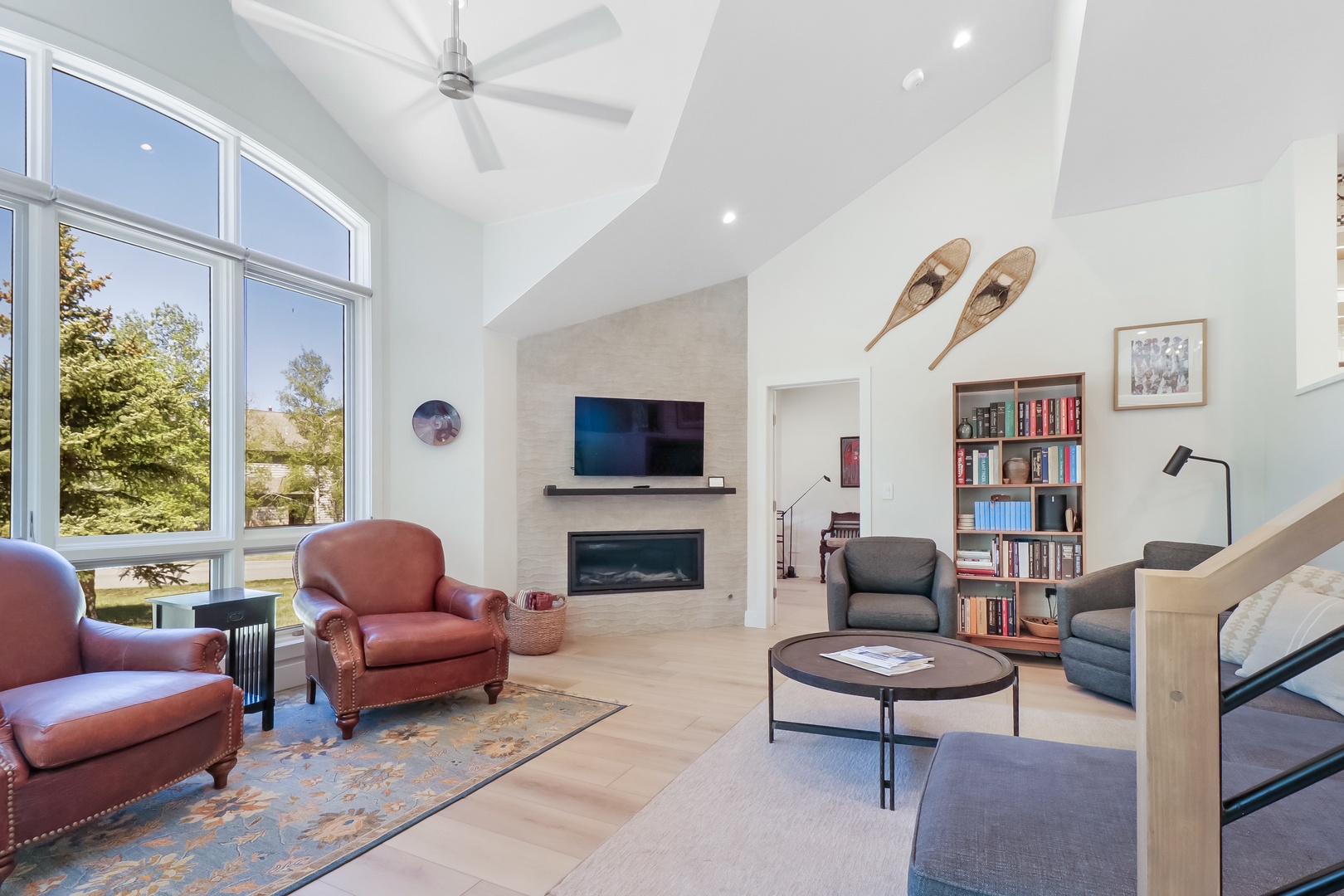 Relax in your bright, spacious living room with soaring vaulted ceilings, a cozy fireplace, and floor-to-ceiling windows framing peaceful natural views.