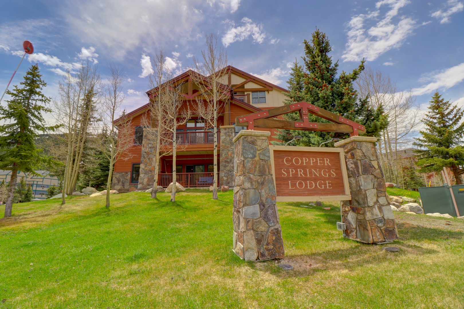 Mountain lodge property featuring rustic timber architecture with stone accents, set among evergreen trees in a peaceful alpine setting.