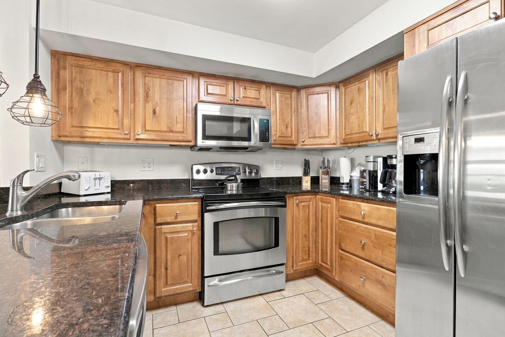 Step into your fully equipped kitchen with warm wood cabinetry and granite countertops, ready for preparing meals with modern appliances and all the essentials you need.
