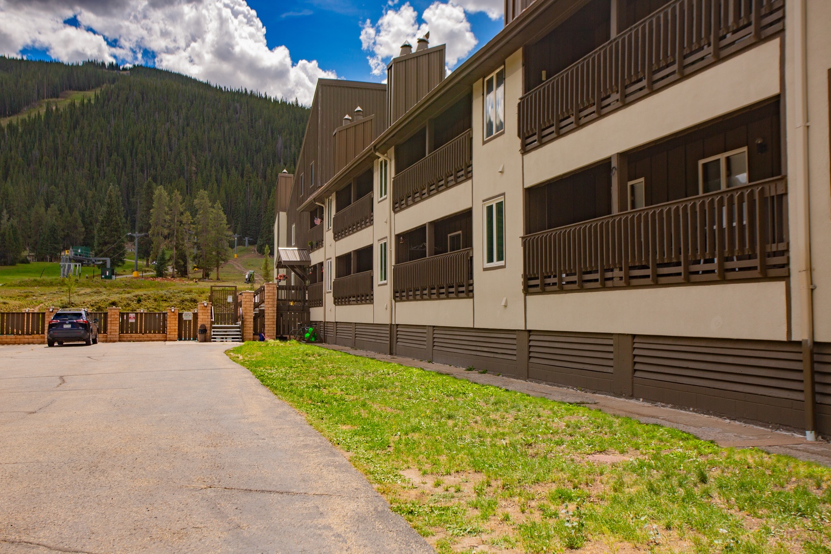 Mountain-side property nestled in a forested area with convenient parking and private balconies overlooking natural surroundings.