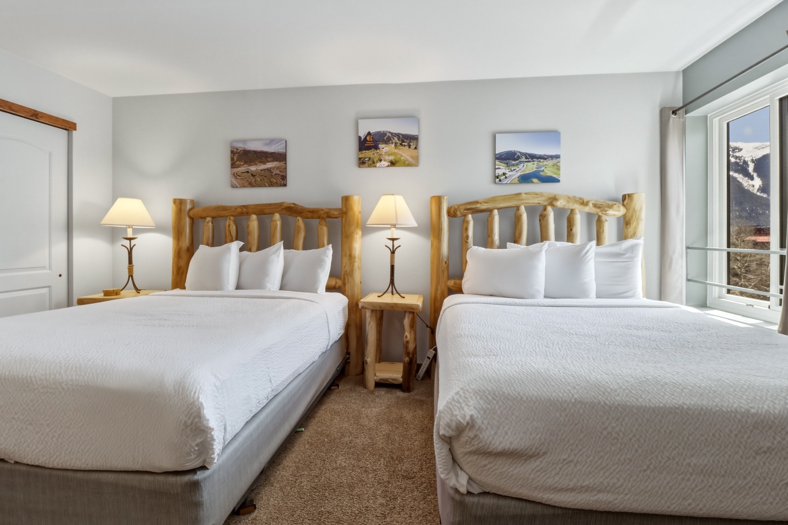 Sink into crisp white linens on rustic log beds, where mountain artwork and warm lighting create your cozy retreat.