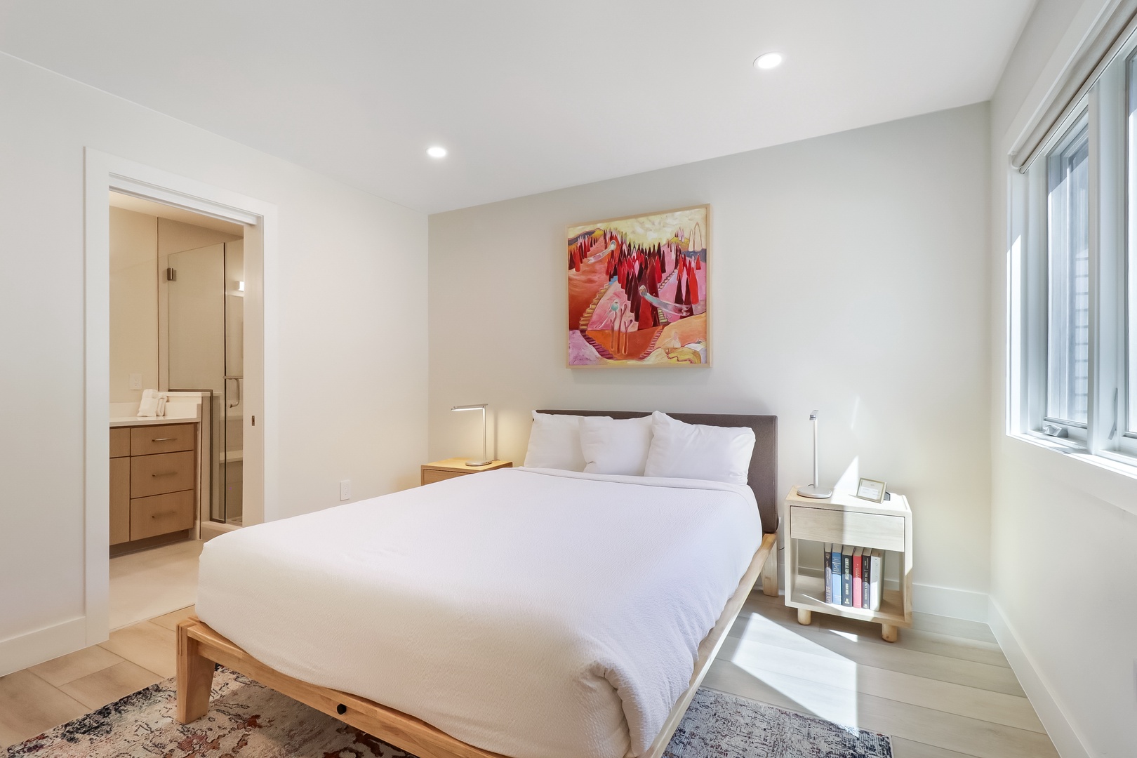 Slip into crisp linens and unwind in your serene bedroom, where soft morning light, warm wood accents, and vibrant art create the perfect retreat after a day of exploring.