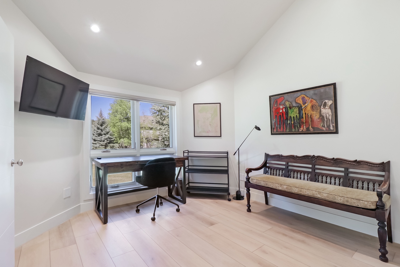 Bright, versatile space with a desk for working, vibrant art for inspiration, and natural light flowing through large windows overlooking greenery—your perfect spot to focus or unwind.