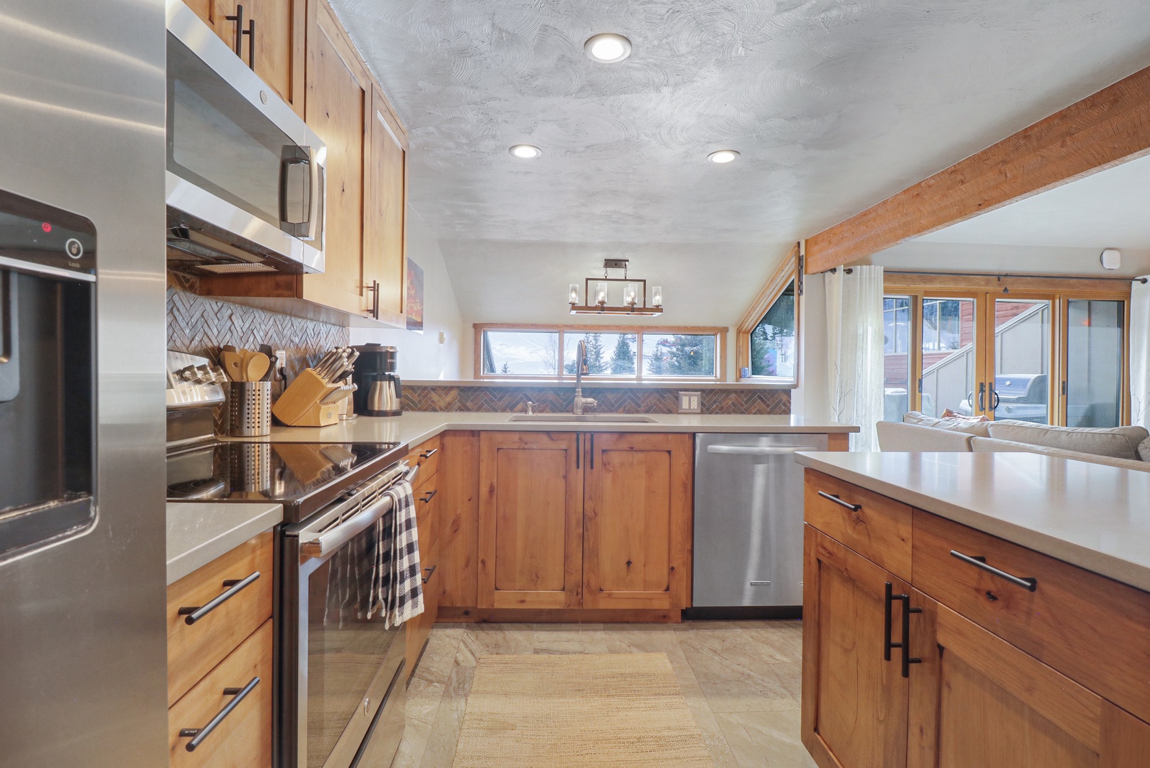 Step into this beautifully designed kitchen where warm wood cabinets and modern stainless steel appliances create the perfect space for your culinary adventures, with natural light streaming through windows that frame lovely outdoor views.