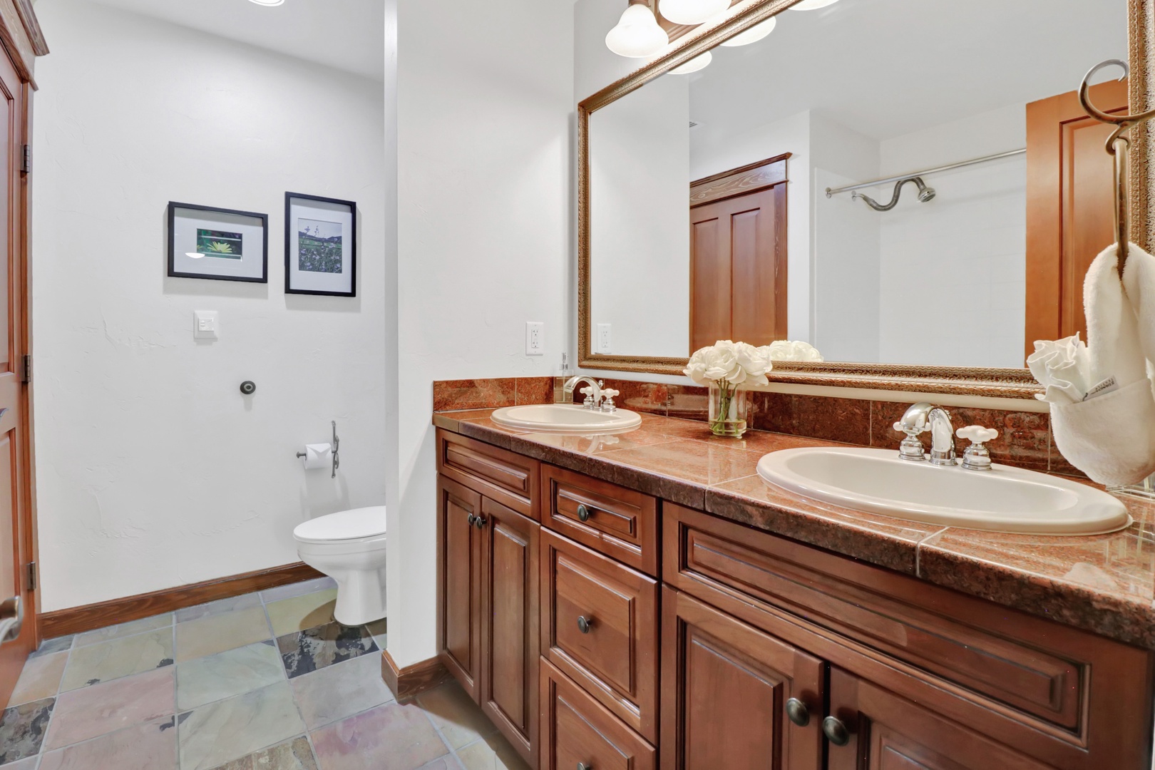 Freshen up in your elegant bathroom featuring double sinks with rich wood cabinetry, gleaming granite counters, and plush towels waiting for you.