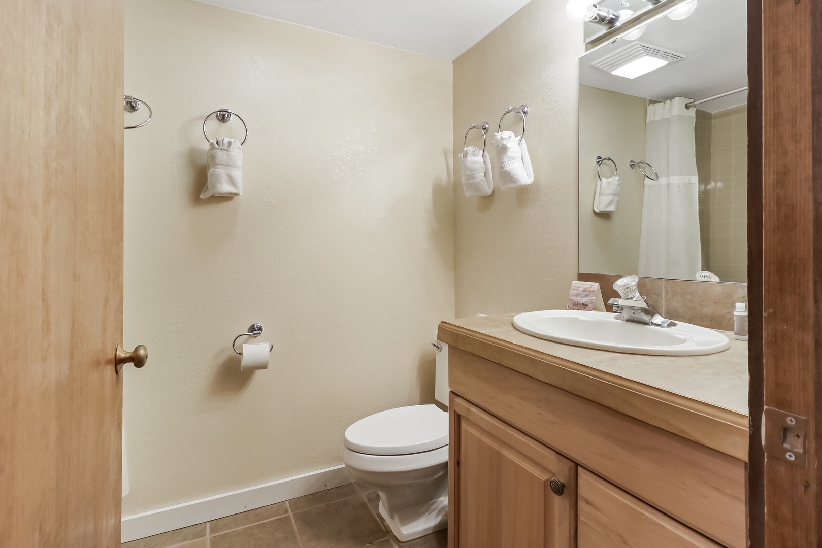 Your private bathroom features warm wood cabinetry and fresh towels, creating a cozy retreat for your daily routines.